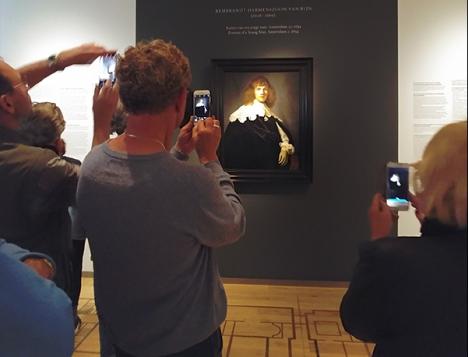 Des visiteurs photographiant <em>Le Portrait de jeune homme</em> de Rembrandt présenté à l'Ermitage d'Amsterdam - Photo Ludovic Sanejouand
