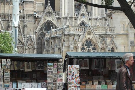 Un passant devant les « boîtes vertes » des bouquinistes situées en face de la cathédrale Notre-Dame de Paris quelques semaines après l'incendie du 15 avril 2019 © Photo LudoSane
