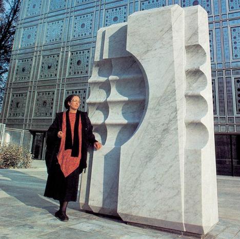 Mona Saudi, à côté de sa sculpture Géométrie de l'esprit, en 1987, sur l'esplanade de l'Institut du monde arabe. © IMA