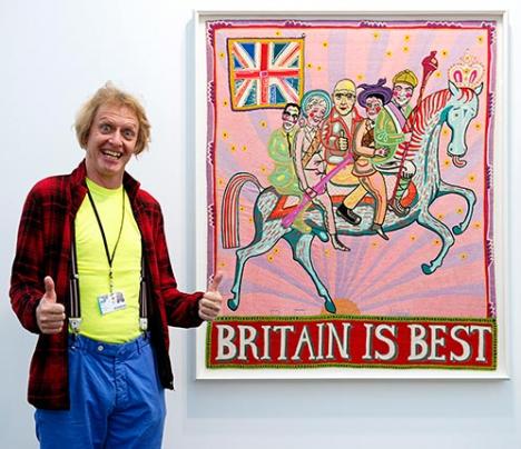 Grayson Perry posant devant une de ses oeuvres accrochée sur le stand de la galerie Victoria Miro à Frieze London 2016 - Photograph by Linda Nylind. Courtesy of Linda Nylind/Frieze.