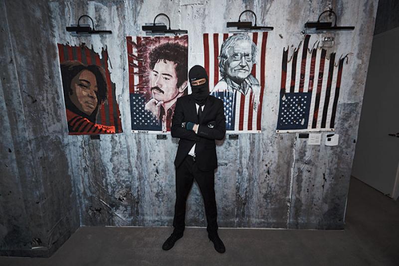 Le directeur artistique de l'installation d'Indecline, « The People’s Prison », devant quatre portraits dans la suite de l'hôtel Trump