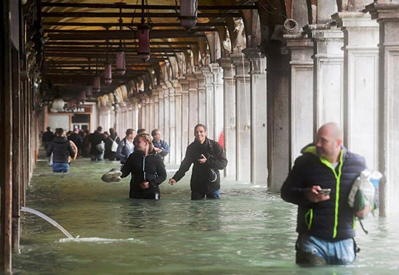 Des touristes sous les arcades de la place Saint Marc à Venise durant l'Acqua Alta, le 29 octobre 2018