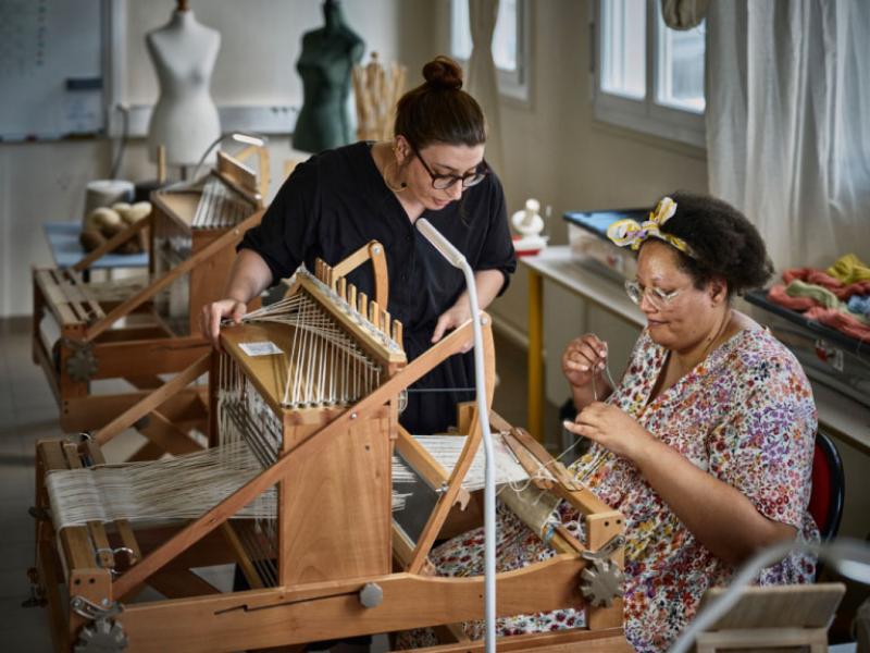 Artisan-formatrice accompagnant une élève dans l'utilisation d'un métier à tisser, au centre de formation de Lainamac. © Julie Limont pour la Fondation Bettencourt Schueller